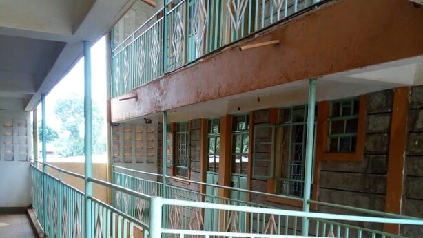 Edifici de diverses plantes amb un balcó al pis superior, amb barana metàl·lica de disseny geomètric i vistes a l'entorn.