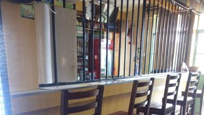 Zona de bar amb cadires de fusta i una barra.