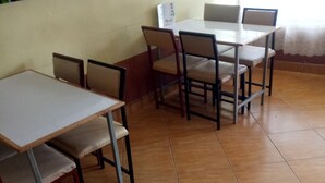 A dining area with multiple tables and chairs, a tiled floor, and a plain wall. - Caldera Suites (Nakuru)