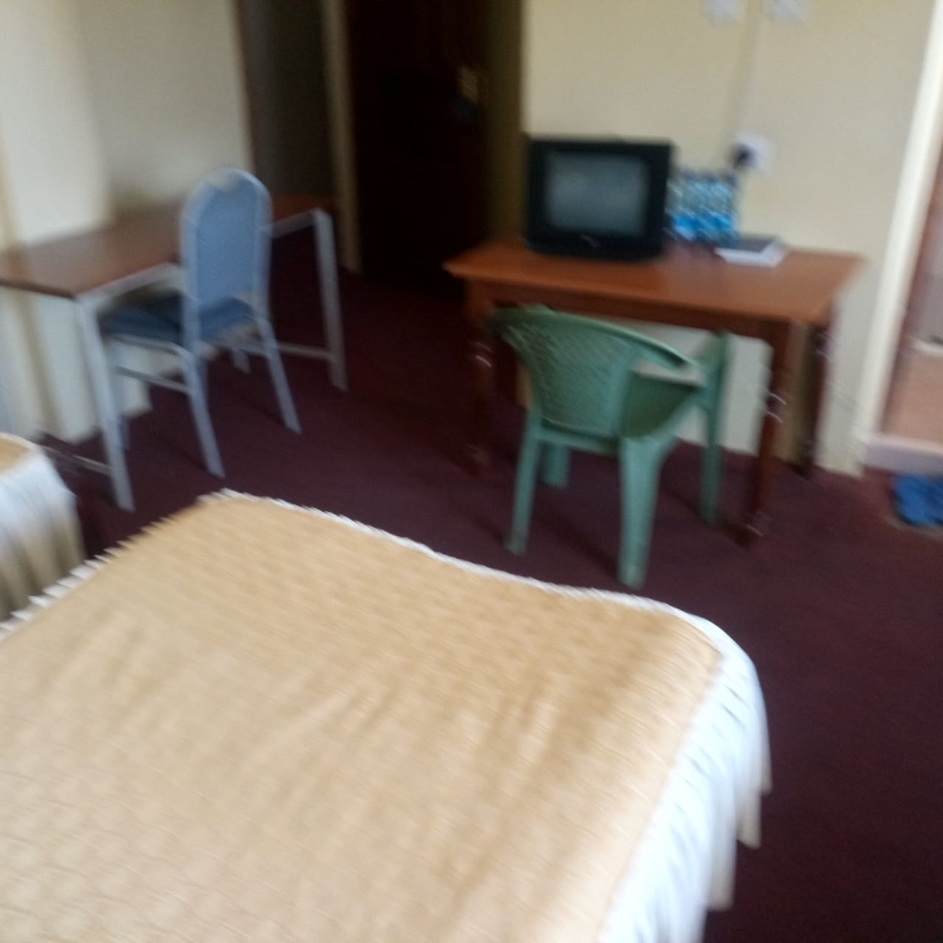 A room with a bed, a desk, a chair, and a television.