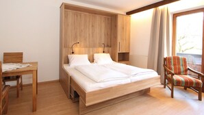 A bedroom with a wooden bed, a desk, and a chair. - Beautiful apartment for 2 people with WIFI, TV, balcony, pets allowed and panoramic view (Fügen)