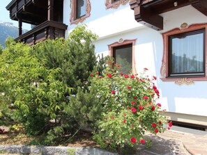 Traditional chalet-style building with a balcony and lush green surroundings.
