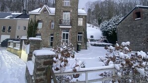 Un edificio de piedra con una torre, rodeado de suelo y árboles cubiertos de nieve.
