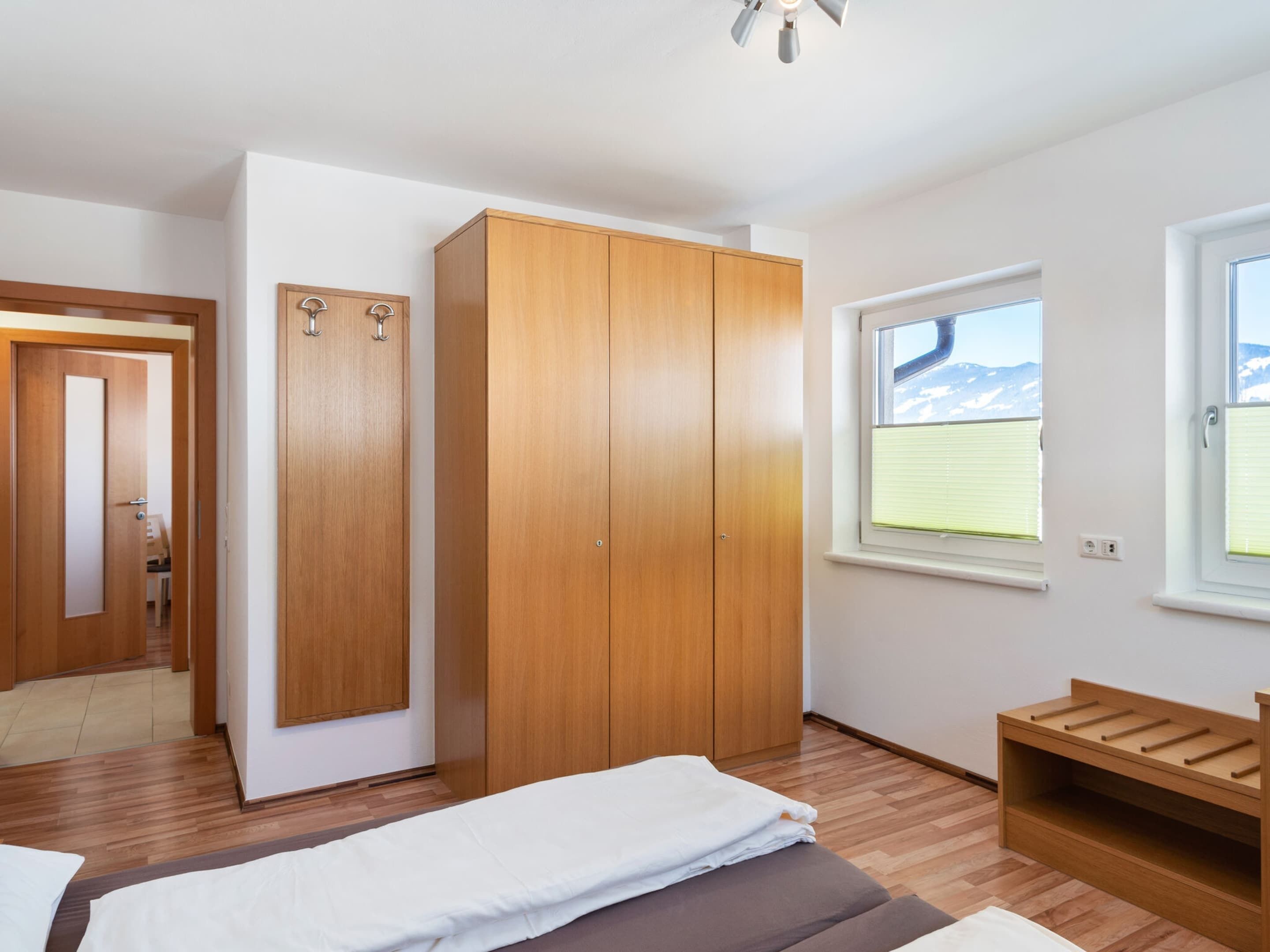 A bedroom with wooden furniture, a bed, a wardrobe, and a window with a view of mountains.