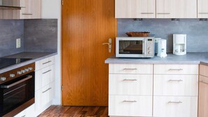 Una cocina compacta con armarios de madera, un microondas, una cafetera y un horno empotrado.