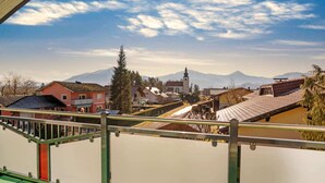 En balkong med utsikt över en stad, med hus, en kyrka och berg i bakgrunden.