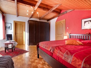 A bedroom with a wooden ceiling, a red wall, a bed with red bedding, a wooden headboard, and a wooden wardrobe. - Apartment in Eberndorf Near Petzen Ski Area (Eberndorf)