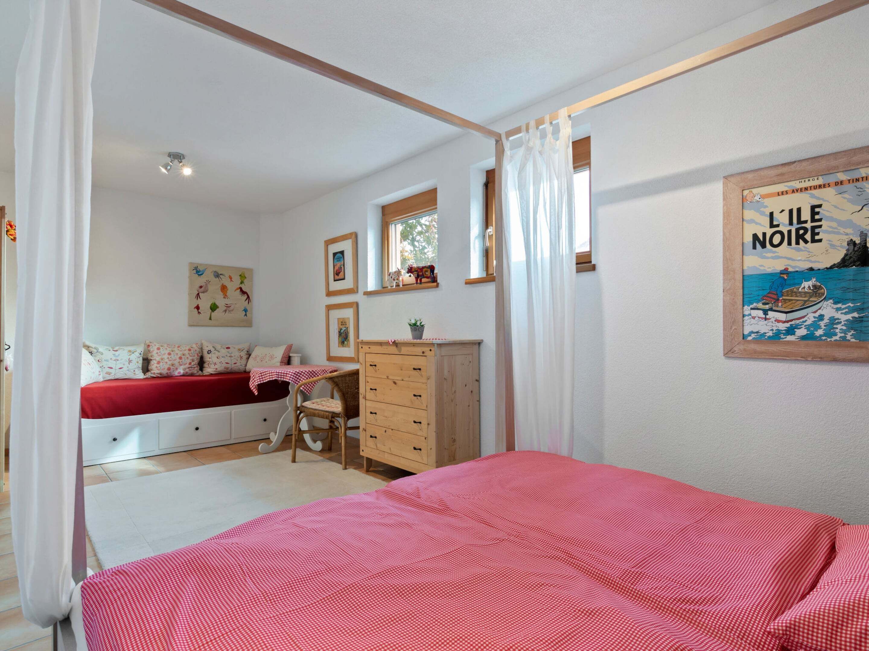 A bedroom with a bed, a desk, a wardrobe, and a window.