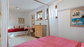 A bedroom with a bed, a desk, a wardrobe, and a window.