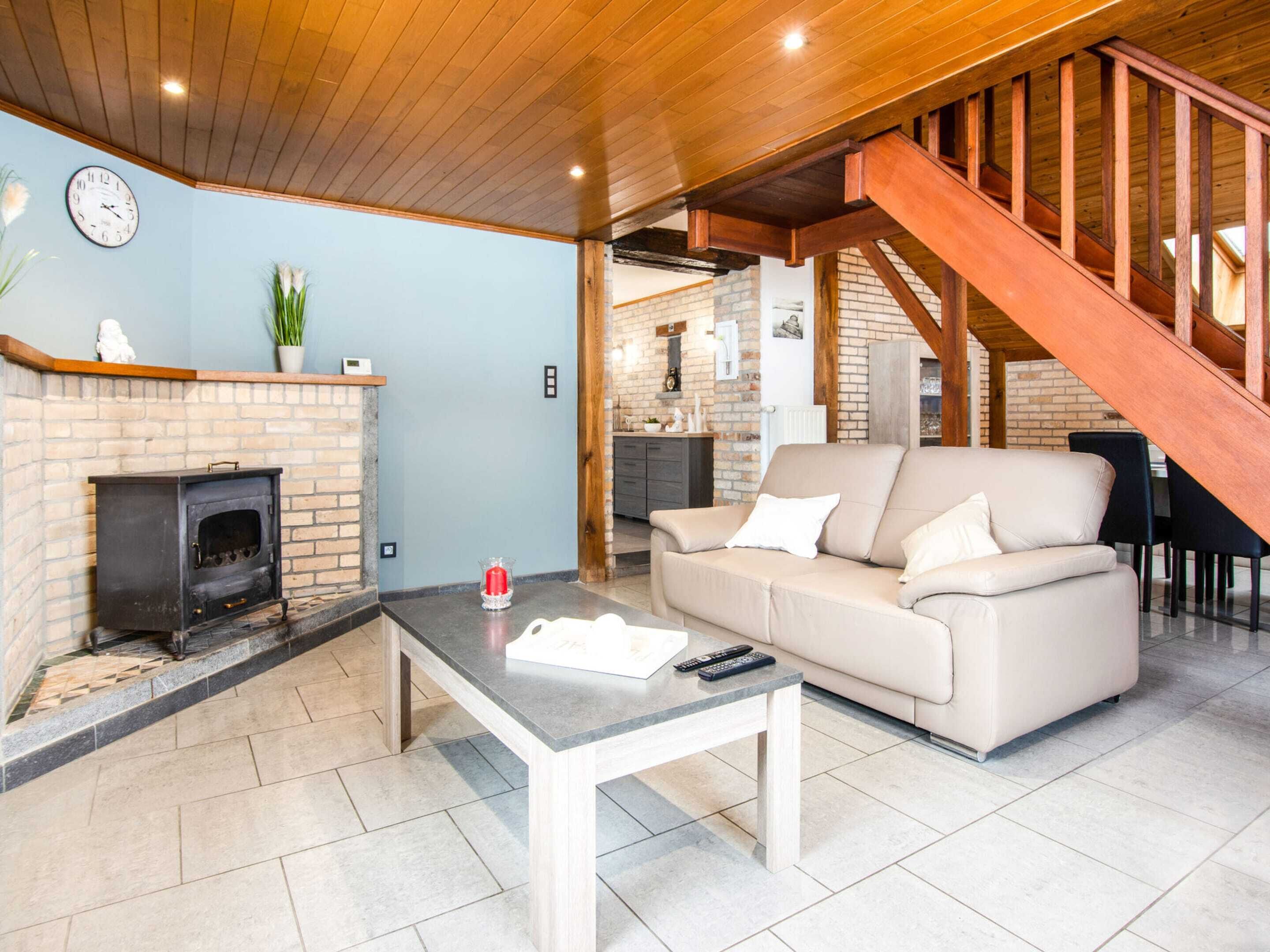 A living room with a fireplace, a sofa, a coffee table, and a staircase.