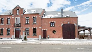 En historisk bygning i mursten med en stor trædør og mange vinduer.