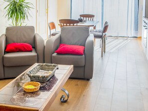 A modern living room with two grey armchairs, each with a red pillow, a wooden coffee table with a basket and a bowl, and a potted plant. - Captivating Cottage in Vielsalm near Forest (Vielsalm)