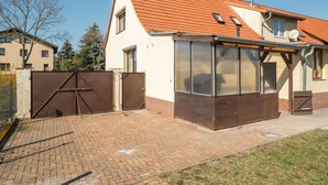 A two-story house with a red-tiled roof, a covered patio area with large windows, and a gated entrance. - Countryside Stay in Meisdorf (Falkenstein)