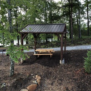 A wooden pavilion with a metal roof, surrounded by trees and a gravel path. - Clean, Modern, Lake Keowee Retreat Near Clemson (Six Mile)