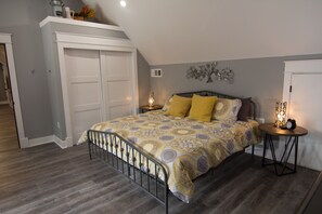 A bedroom with a bed, a nightstand, a wall-mounted clock, and a ceiling light. - Clean, Modern, Lake Keowee Retreat Near Clemson (Six Mile)