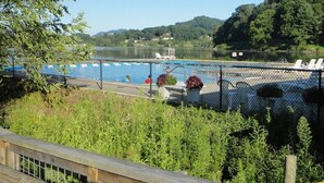 En inhägnad pool med solstolar, omgiven av grönska och kullar i bakgrunden.