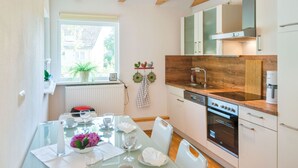 A modern kitchen with wooden beams, a built-in oven, and a window with a view of a house. - Tranquil Holiday Home in Winsen near River (Winsen an der Aller)