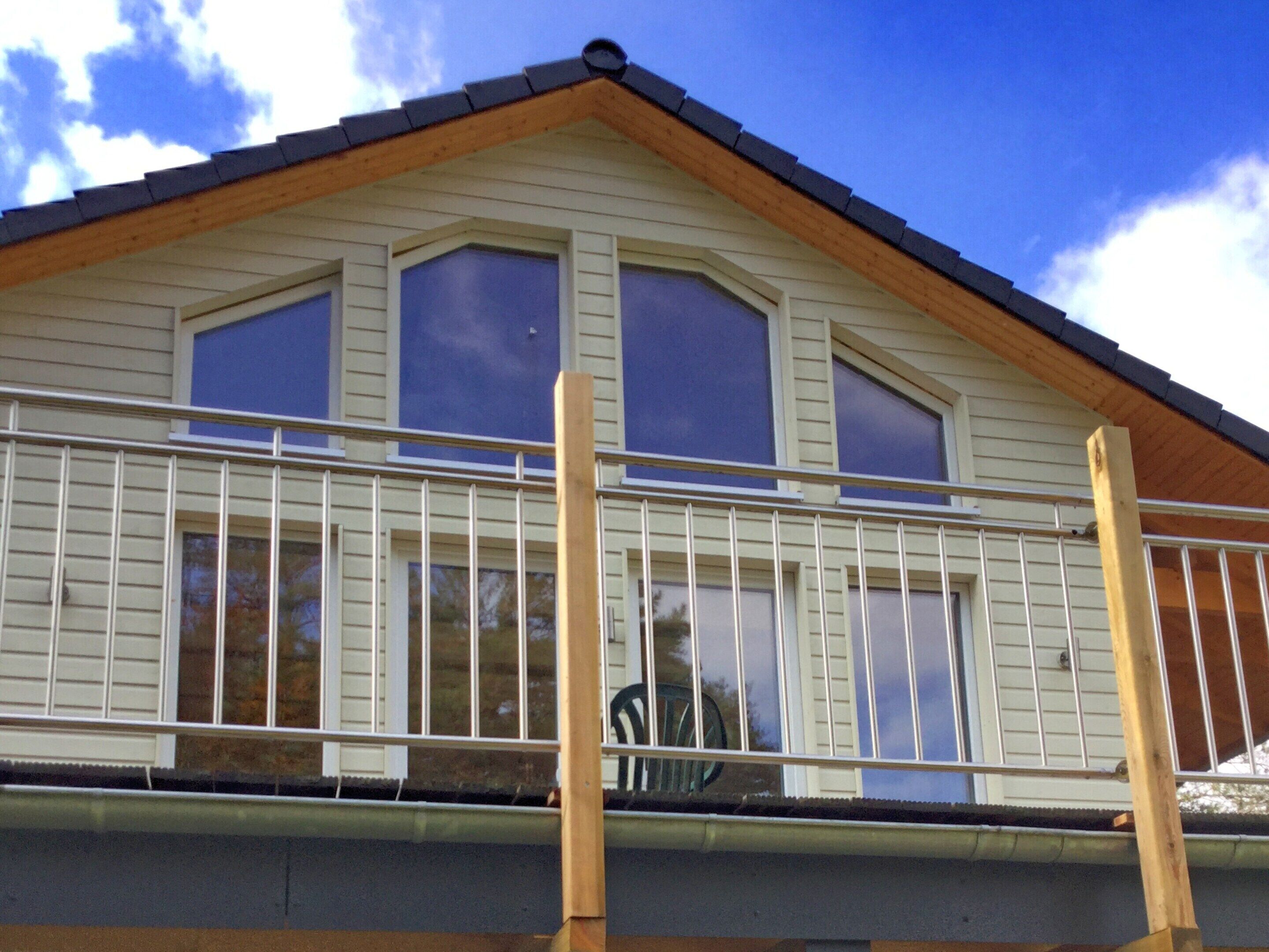 A two-story building with a balcony, large windows, and a wooden roof.