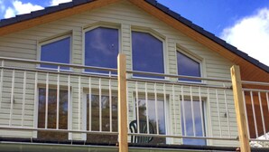 Ein zweistöckiges Gebäude mit Balkon, großen Fenstern und einem Holzdach.