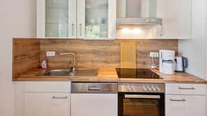 A compact kitchen with wooden countertops, a built-in dishwasher, a stove, and a coffee maker. - Tranquil Holiday Home in Winsen near River (Winsen an der Aller)