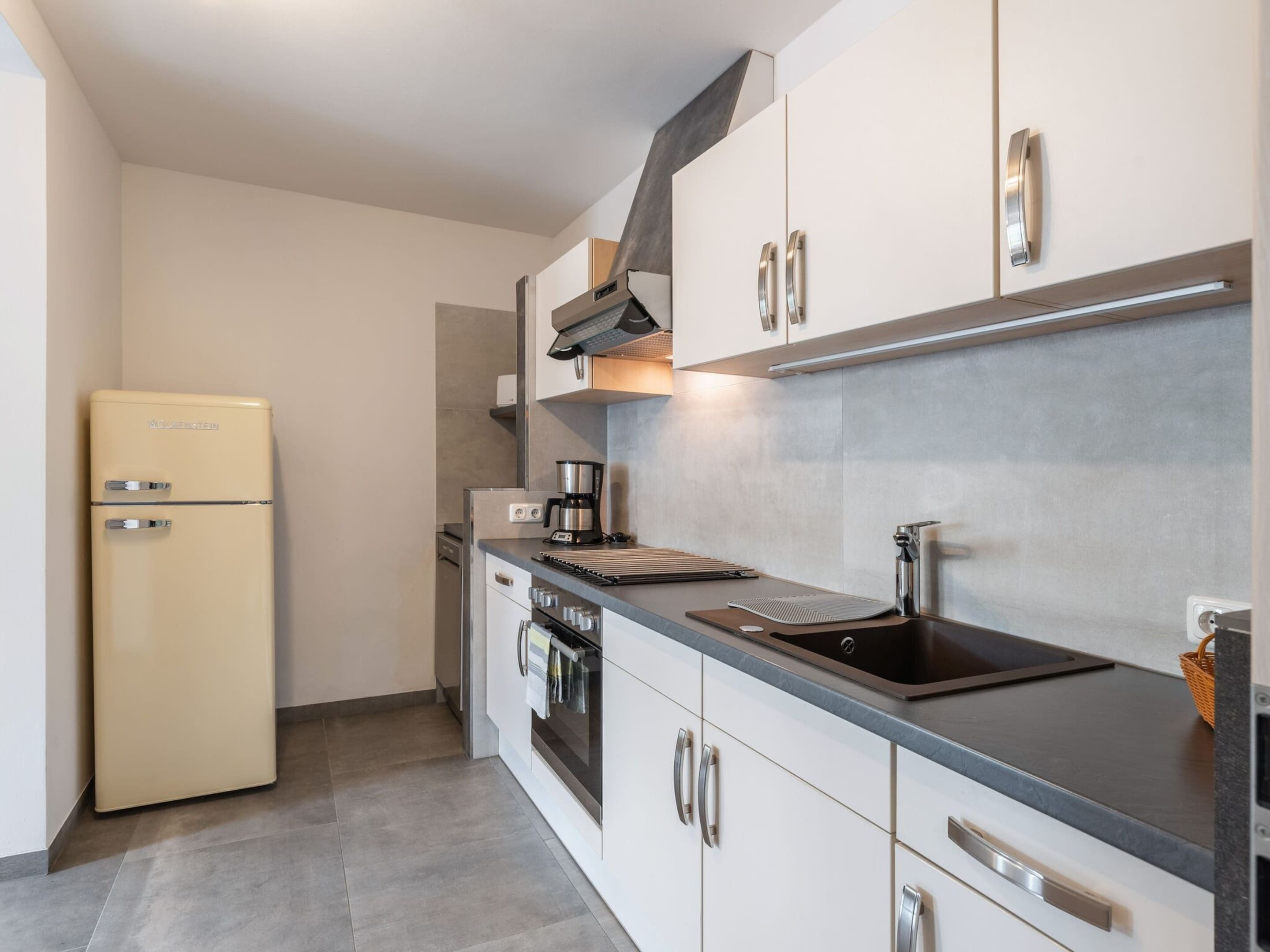 A modern kitchen with a built-in oven, a coffee maker, and a sink.