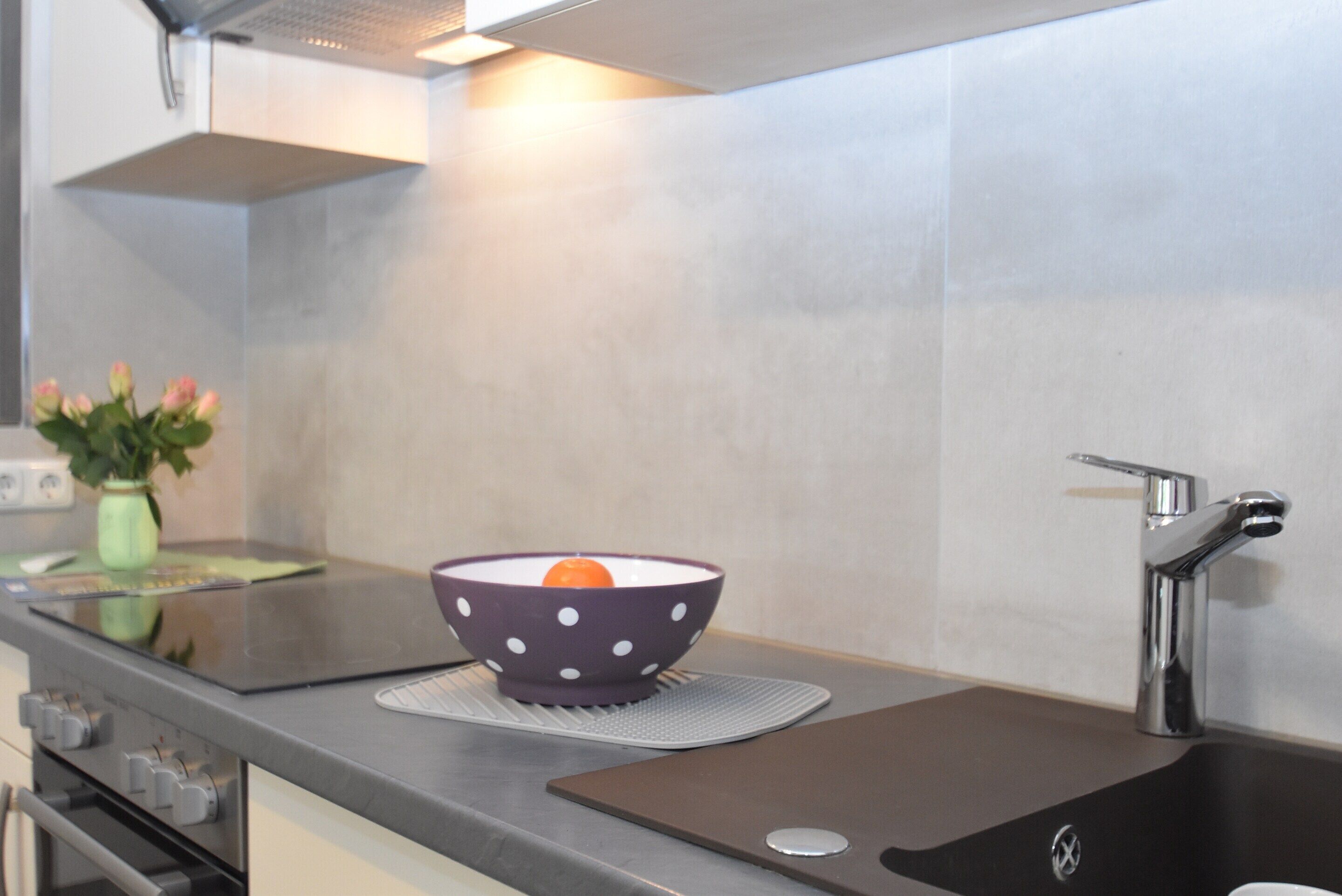 Una cocina con estufa moderna, un lavamanos y un tazón estampado con lunares sobre la encimera.