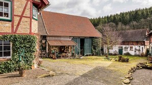 A traditional half-timbered house with a gravel courtyard, surrounded by trees and a forested hillside. - Escape Near River, Wolfsberg (Sangerhausen)