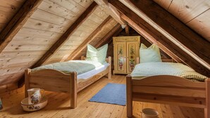 A cozy attic bedroom with two wooden beds, a wooden wardrobe, and a small table with a bowl. - Escape Near River, Wolfsberg (Sangerhausen)
