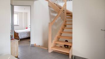 Una escalera que conduce a un dormitorio con una cama y un aparador.