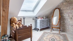 A bedroom with a skylight, a wooden bed, a dresser, a mirror, and a patterned rug. - Renovated Village House With Enclosed Garden (Saint-Louis)