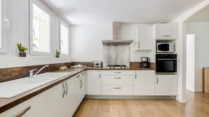 A modern kitchen with white cabinets, a stainless steel sink, a microwave, and a stove. - Holiday Home in Barry-d'islemade With Pool (Barry-d'Islemade)