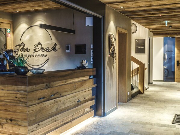 Een receptiebalie met een houten afwerking, een bordje aan de muur met de tekst 'The Beck' en een trap die naar een ander gebied leidt.