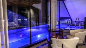 Un interior modern amb una banyera d'hidromassatge tancada amb vidre, una llar de foc i zones de seients confortables.