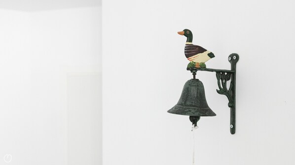 A wall-mounted bird figurine with a bell.