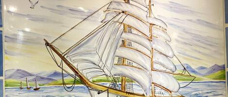 A sailing ship with multiple sails, a cabin, and an anchor.
