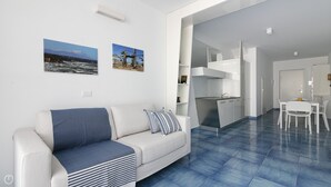Una sala de estar moderna con un sofá, un comedor con mesa y sillas, y una cocina con estufa y alacenas.