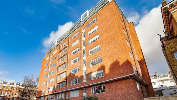 Un edificio de ladrillo de varios pisos con techo plano y ventanas amplias.