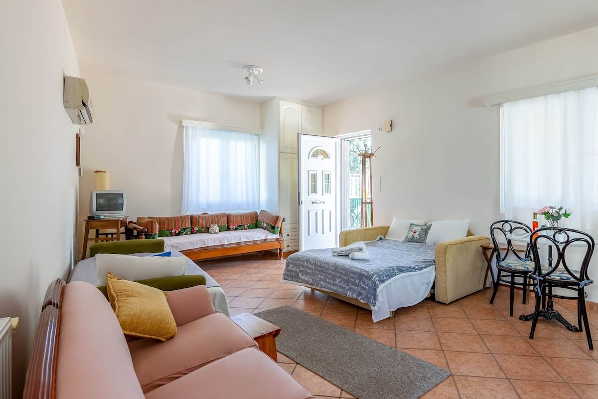 Une pièce spacieuse et bien éclairée, comprenant un lit, un canapé et une petite table avec des chaises.