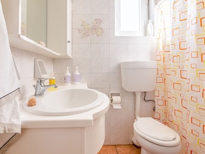 A bathroom with a white sink, toilet, and shower curtain.