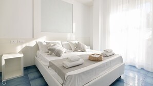 Un dormitorio moderno con una cama grande, ropa de cama blanca y una mesita de noche.
