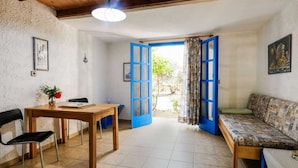 A room with a wooden ceiling, a dining table with chairs, a sofa, and a large open door leading outside. - Tranquil Holiday Home in Palaiochora near Sea Beach (Kantanos-Selino)