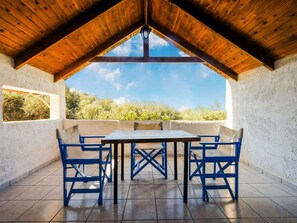 Un patio al aire libre con techo de madera, una mesa y sillas azules.
