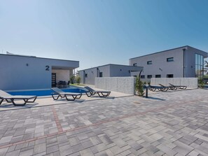 En modern byggnad med en swimmingpool och solstolar.