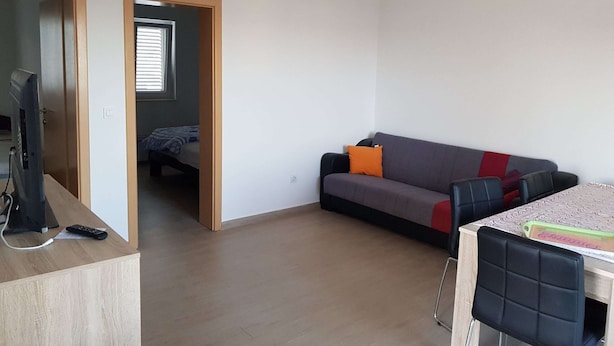 A small, open-plan living space with a sofa, a table, and a TV. - Contemporary Apartment in Neviđane near Sea  (Pasman)