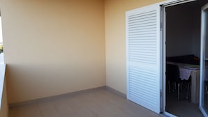 A balcony with a tiled floor, a sliding door, and a table with chairs inside. - Contemporary Apartment in Neviđane near Sea  (Pasman)