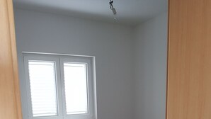 A bedroom with two beds, a window, and a bedside table. - Contemporary Apartment in Neviđane near Sea  (Pasman)