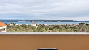 Un balcon offrant une vue sur un paysage côtier, comprenant des maisons et une étendue d’eau.