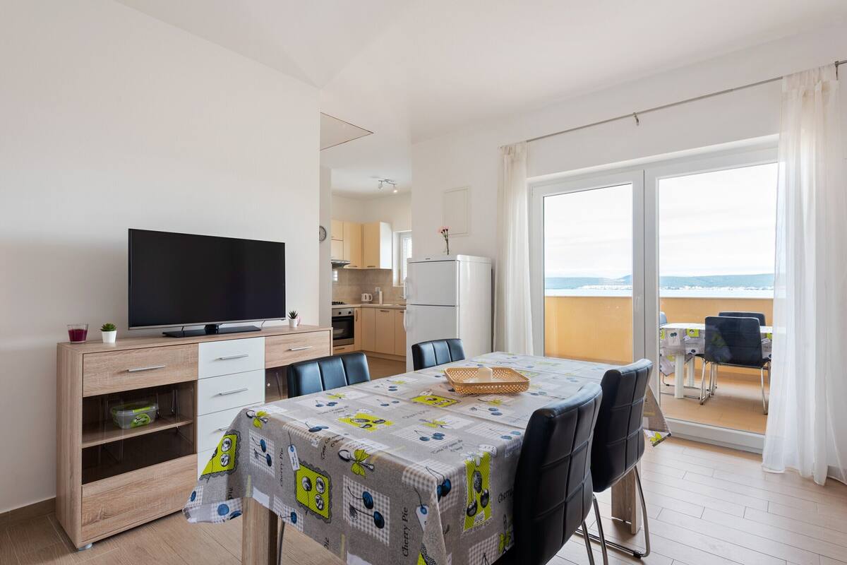 A modern apartment with a dining area, kitchen, and balcony with a view.