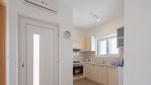 Une cuisine moderne avec des meubles blancs, une cuisinière, un four et une fenêtre équipée de stores.