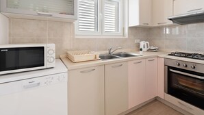 A modern kitchen with a microwave, dishwasher, sink, and stove. - Simplistic Apartment in Neviđane with Balcony  (Pasman)